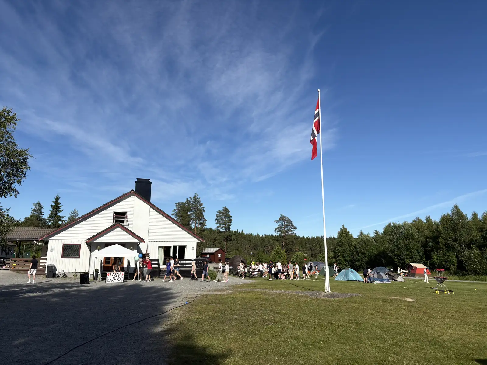Degernes leirsted med hovedbygget, flagget og mennesker ute på leir